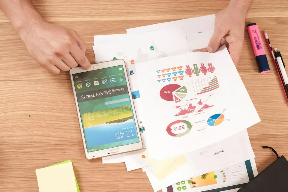 Printed charts and a tablet showing financial reports on a desk